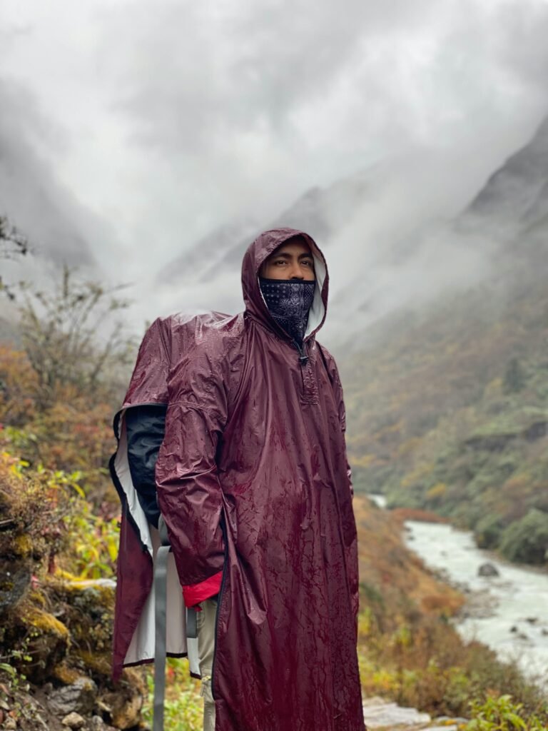 Explorer in a raincoat trekking through misty mountains in Nepal, showcasing adventure and nature.