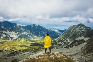 A lone traveler in a yellow raincoat admires the breathtaking mountain views in Romania.